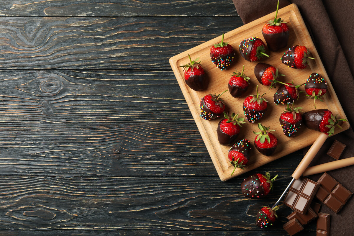 Chocolate fondue. Strawberry in chocolate on wooden background, top view