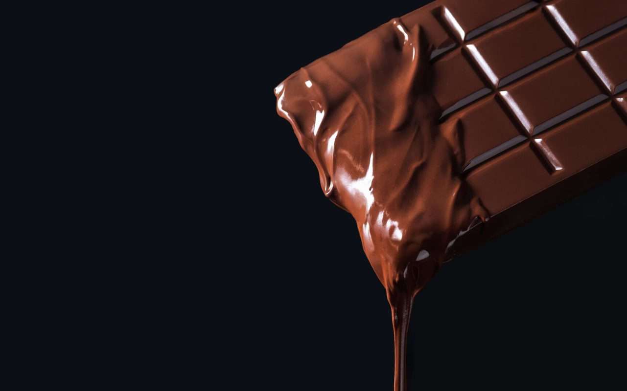 Dripping melted chocolate bar on dark background