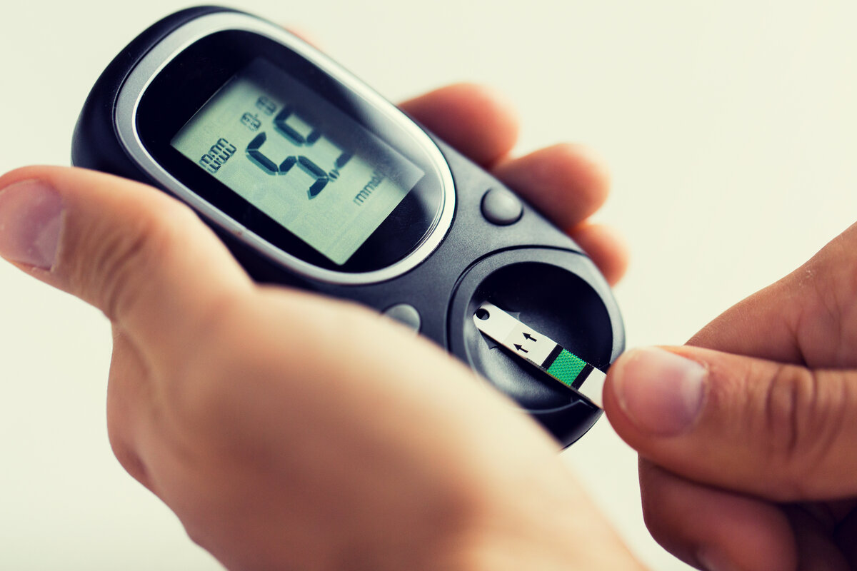 close up of man checking blood sugar by glucometer