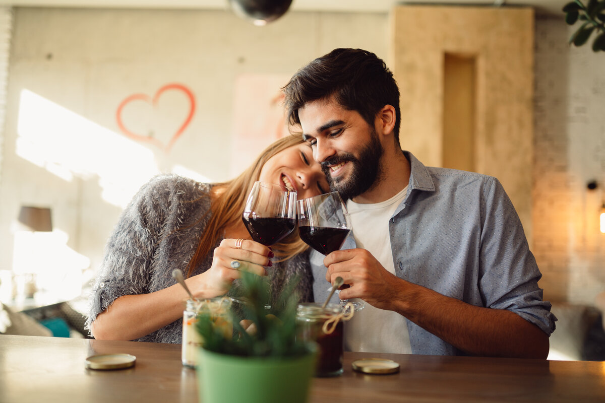 Cheers! Happy couple is drinking wine at cafe during a day